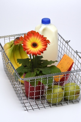 Orange and yellow daisy inside a shopping basket filled with groceries